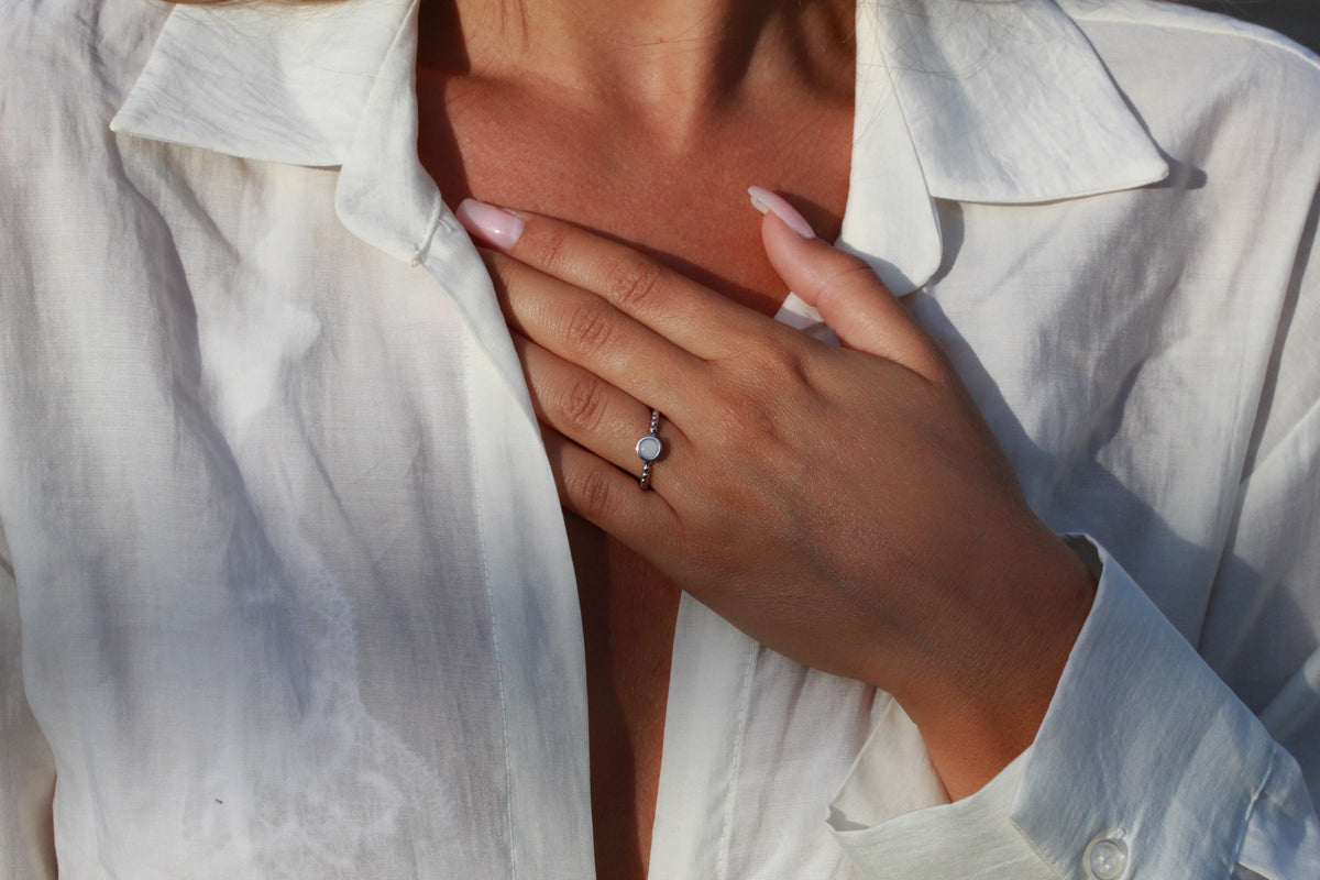 Gros plan d'une main portant la bague Isabelle en argent sur une chemise blanche