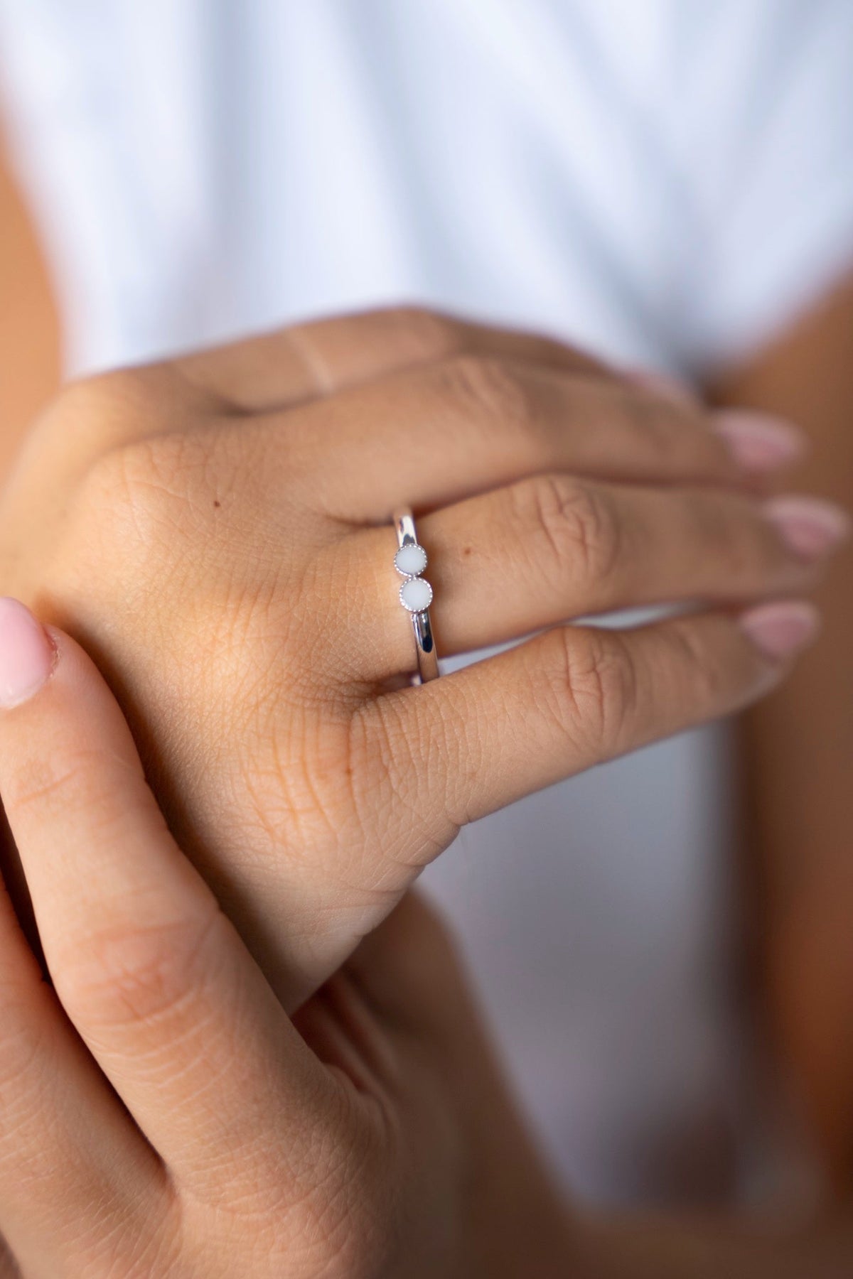 Bague Bo en argent avec deux petites pierres de lait maternel côte à côte, portée à l'annulaire.
