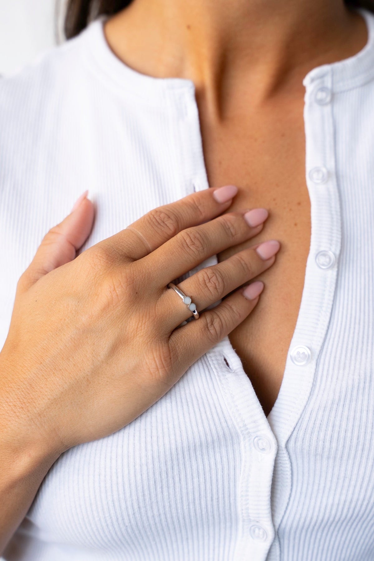 Femme en gilet côtelé blanc, la main sur la poitrine, avec la bague Bo en argent 925.