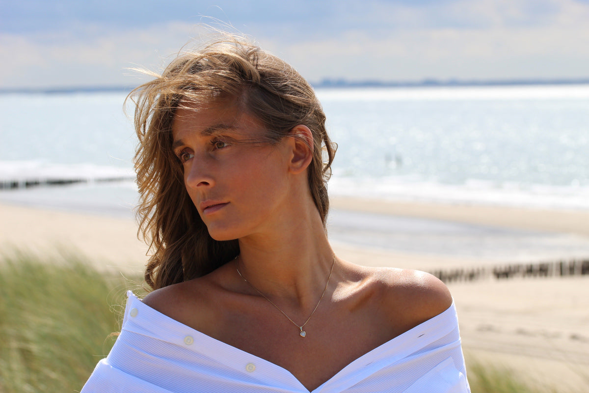 Femme au bord de la mer portant le pendentif cœur Cara argenté sur une fine chaîne