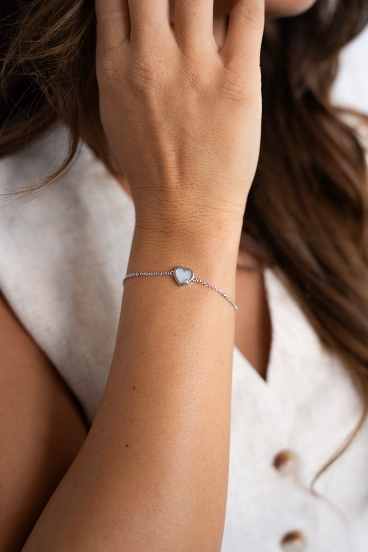 Gros plan du bracelet au lait maternel Esmée en argent avec un cœur sur une fine chaîne.