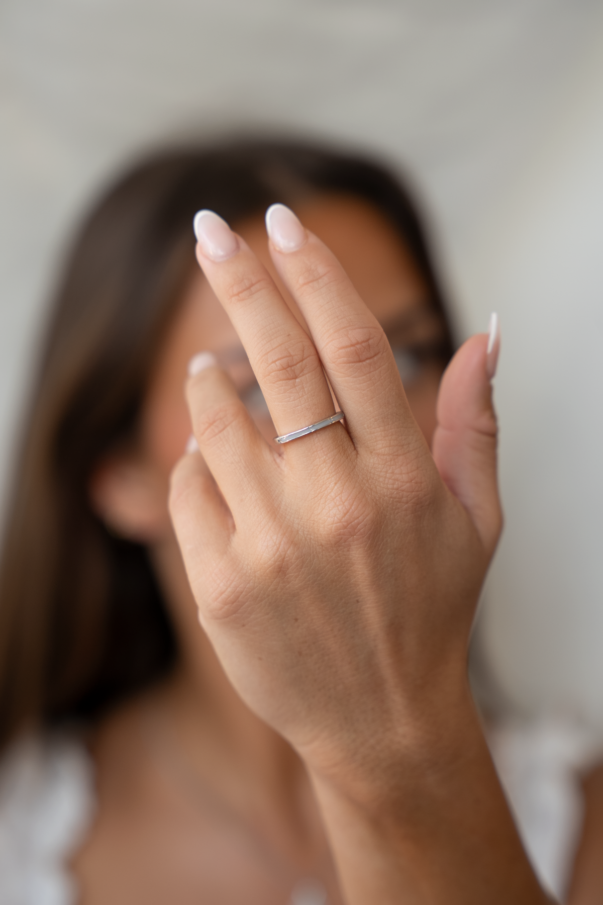 Main levée devant le visage portant la bague Eva en argent à ligne de lait