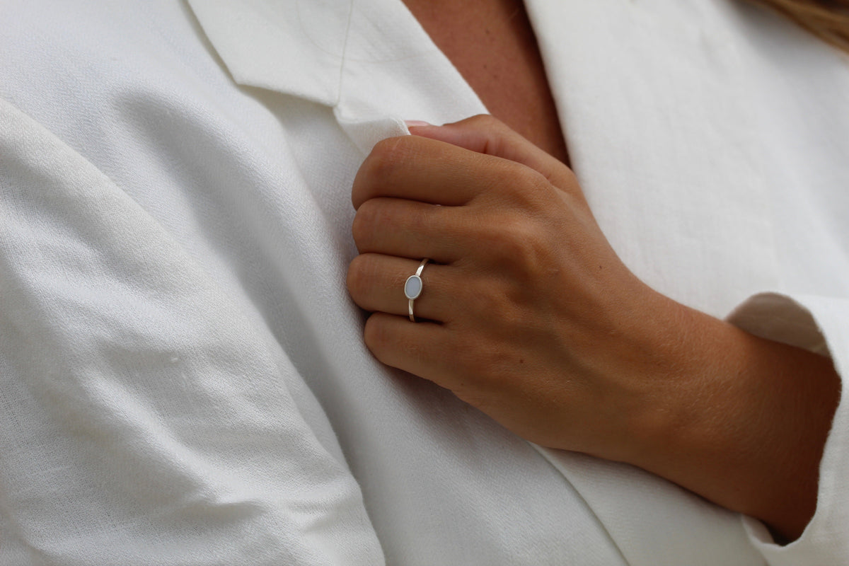 Gros plan d'une main portant la bague Juna en argent, tenant le revers d'une veste blanche