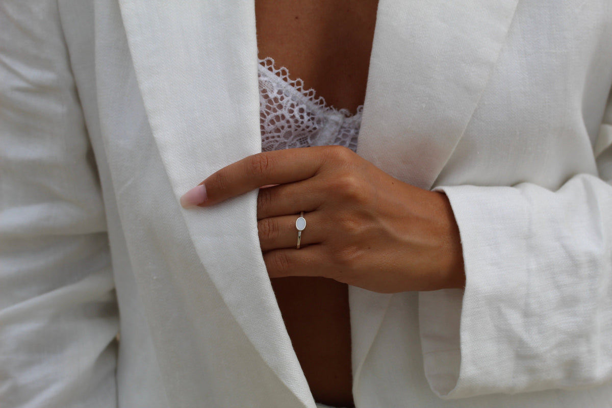 Bague Juna en argent portée, main tenant le revers d'une veste en lin blanc