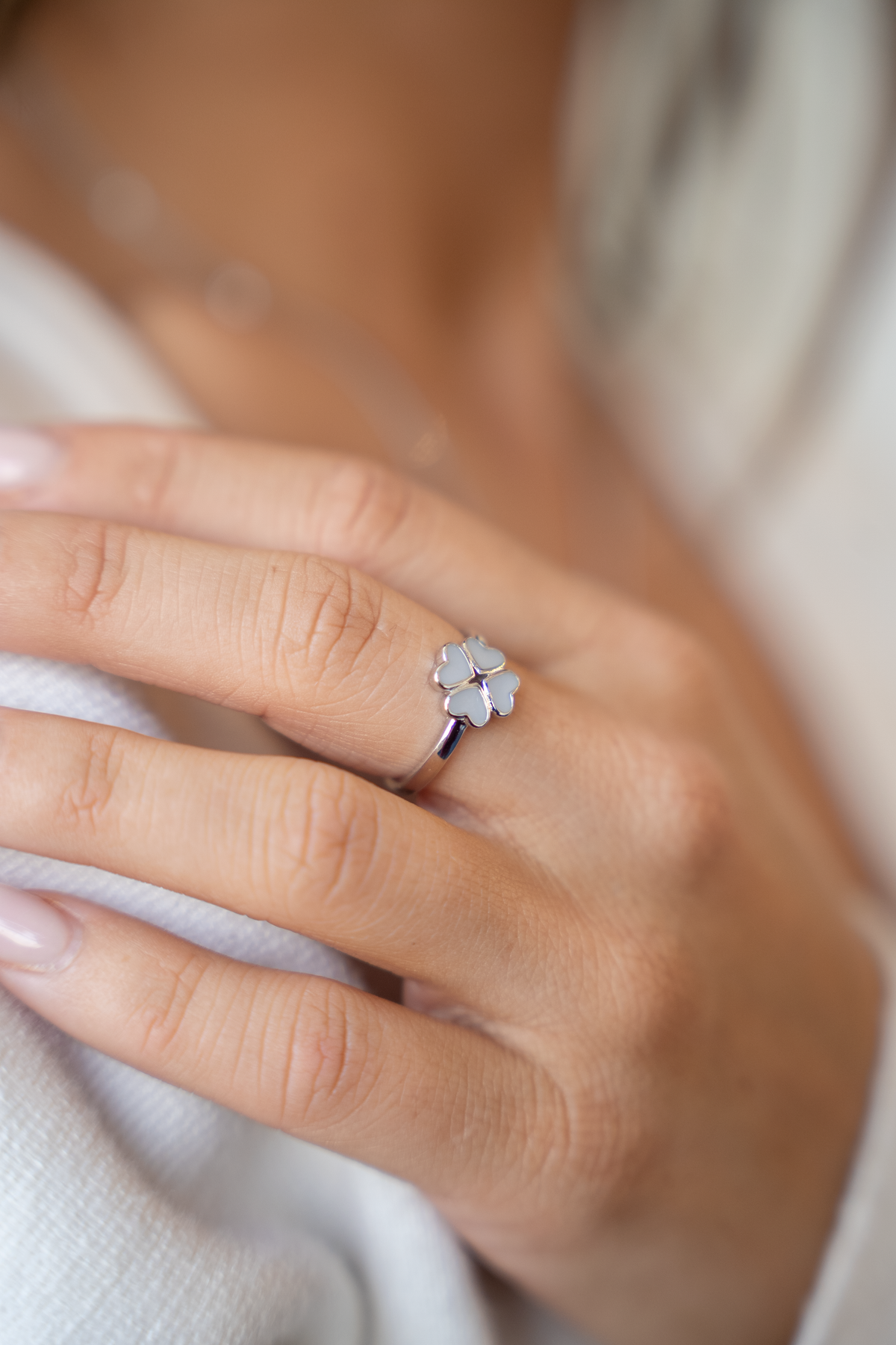 Gros plan de la bague trèfle Lucy couleur argent portée au doigt, quatre cœurs en lait maternel