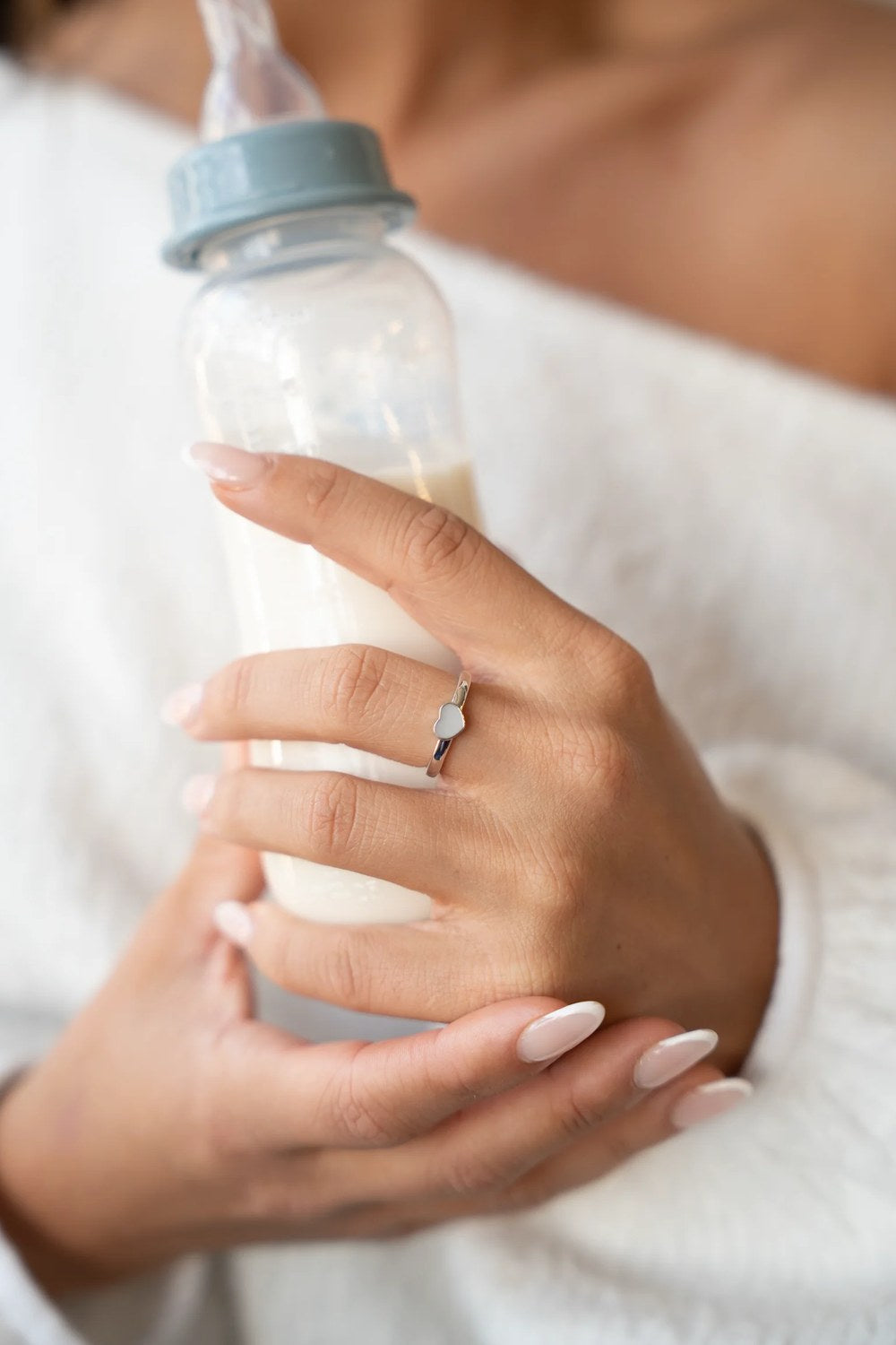 Maman tenant un biberon de lait maternel et portant une bague au lait maternel